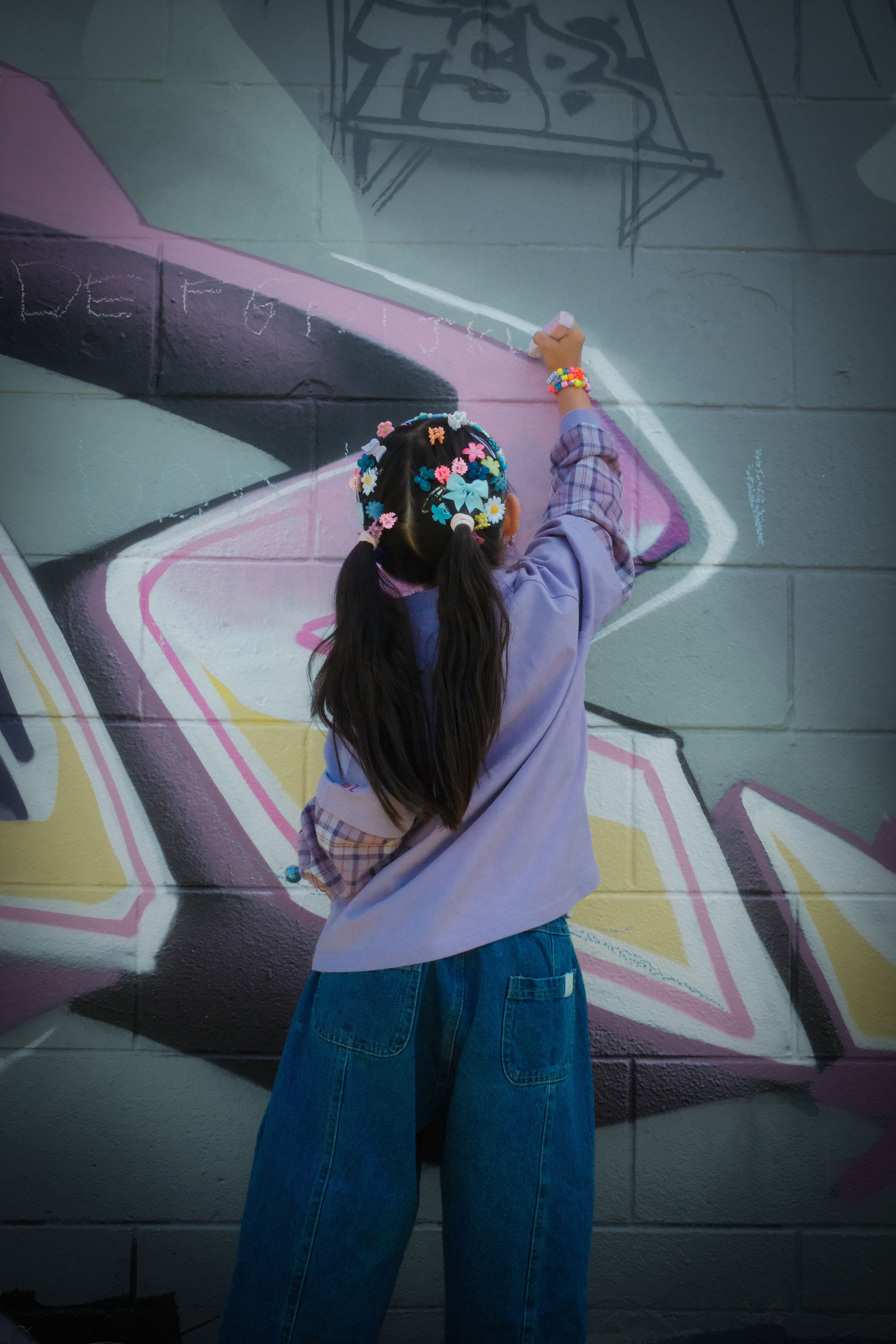 Child modelling unique kids top Ollie double-sleeve in purple fig in front of graffiti wall — From Y To Z kidswear NZ
