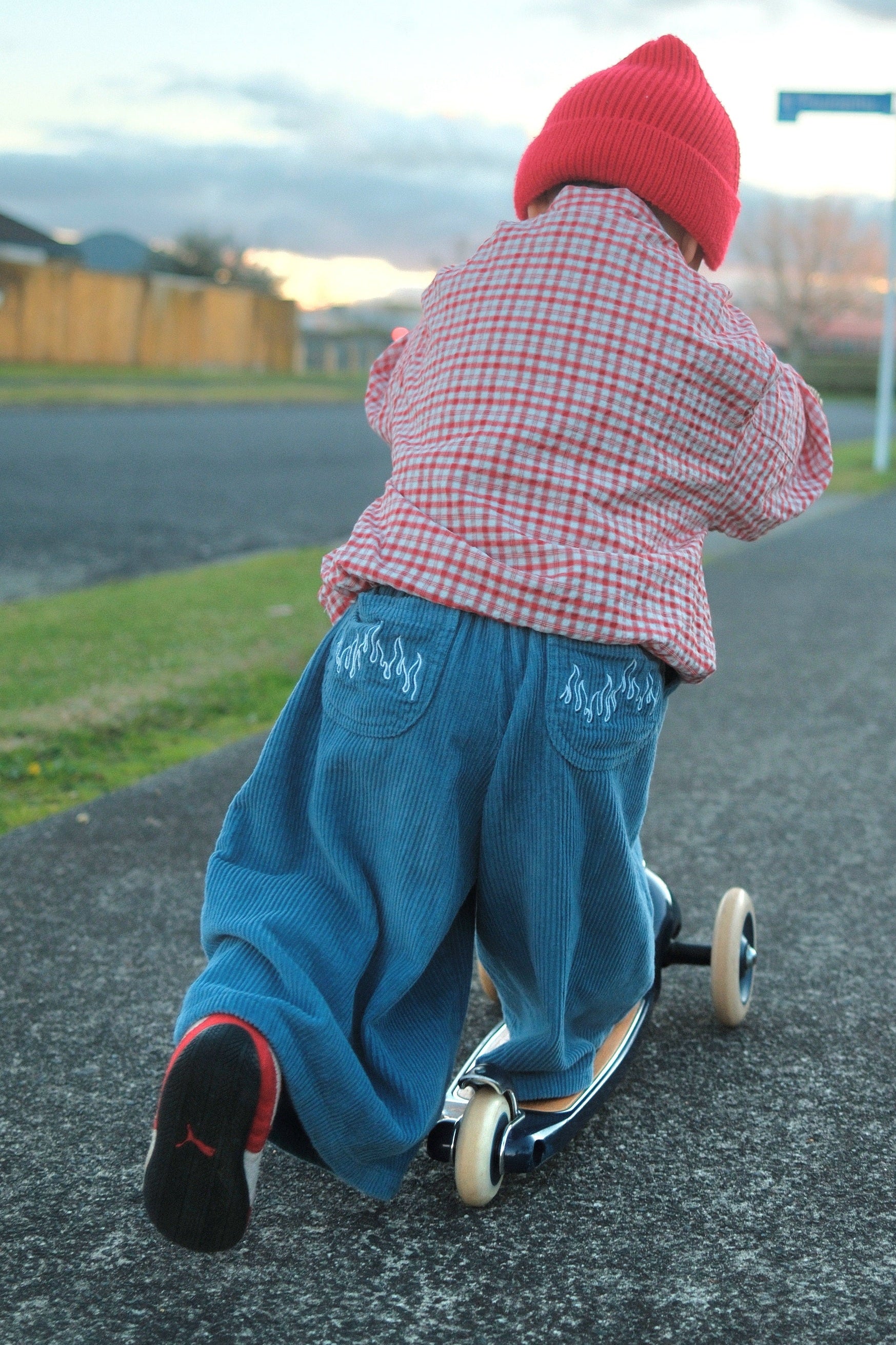 Toddler riding scooter wearing Blaze cord pants in blue flame