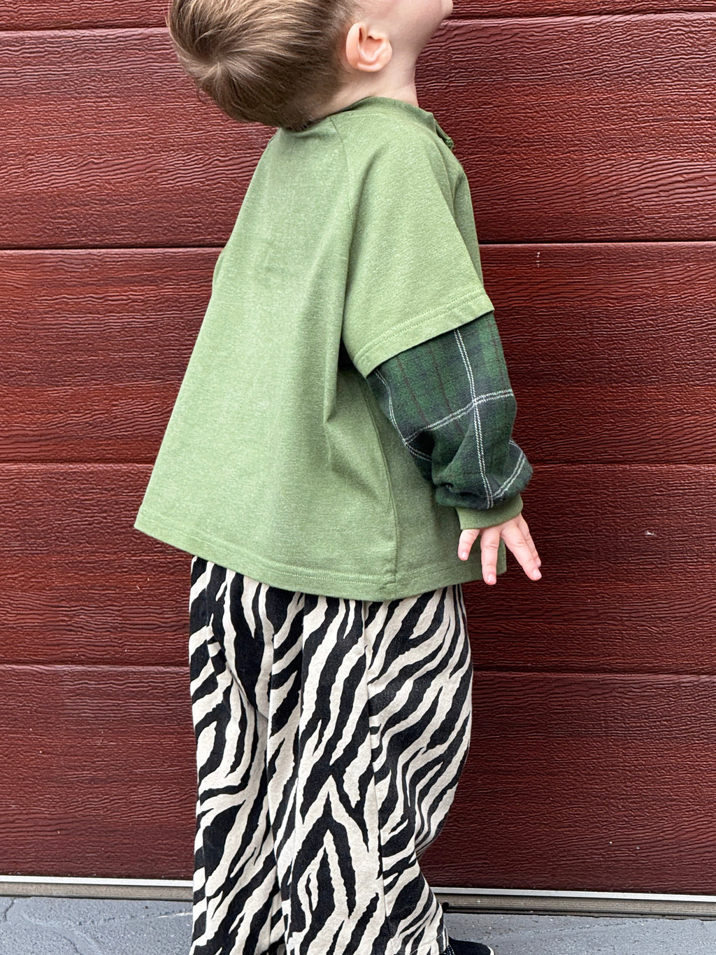 Toddler pictured wearing green ollie double-sleeve in Hunter 